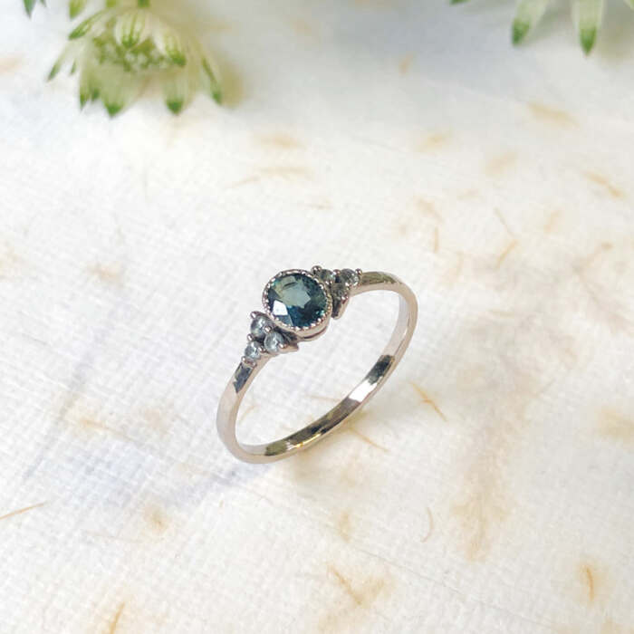 La bague Laura en or gris palladié 18 carats faimined sertie d'un saphir teal blue et de 6 saphirs verts, pièce unique taille 53